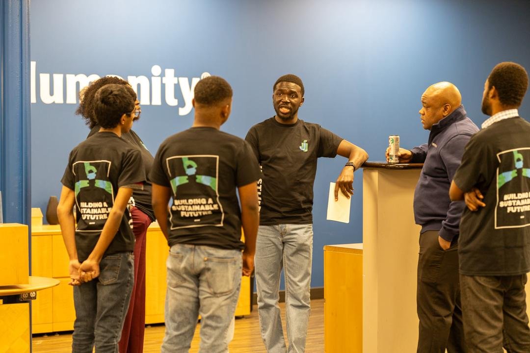 Five people, most in JustUsedTech shirts, standing in conversation around a high table in a community space. (Saint Louis, Missouri)
