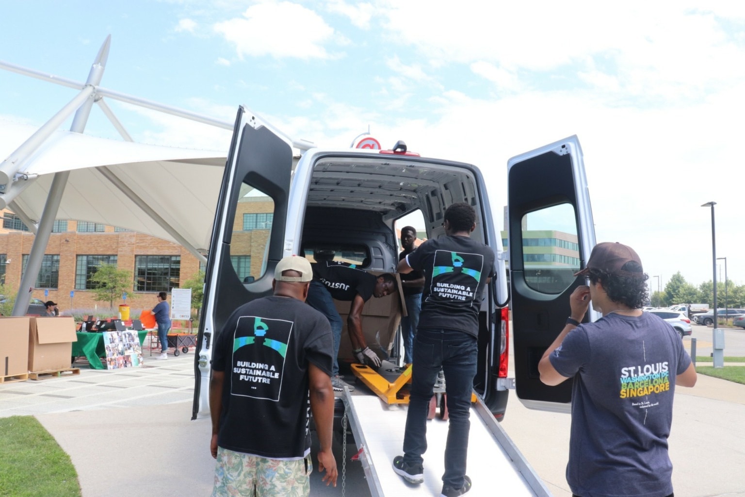 Team members loading equipment into the back of a van at an outdoor collection event.