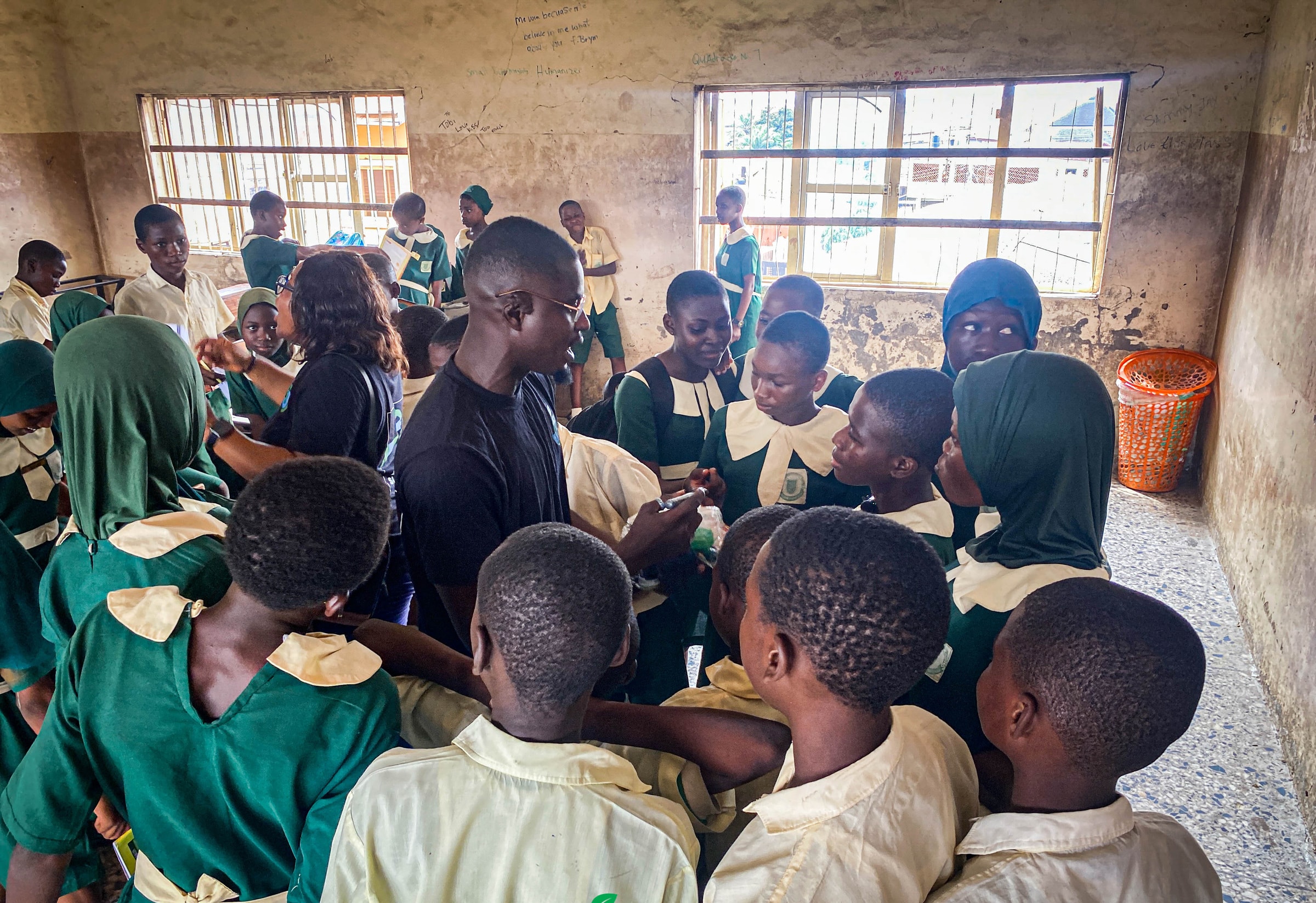 Students in green and cream uniforms crowded together inside a classroom during a session.