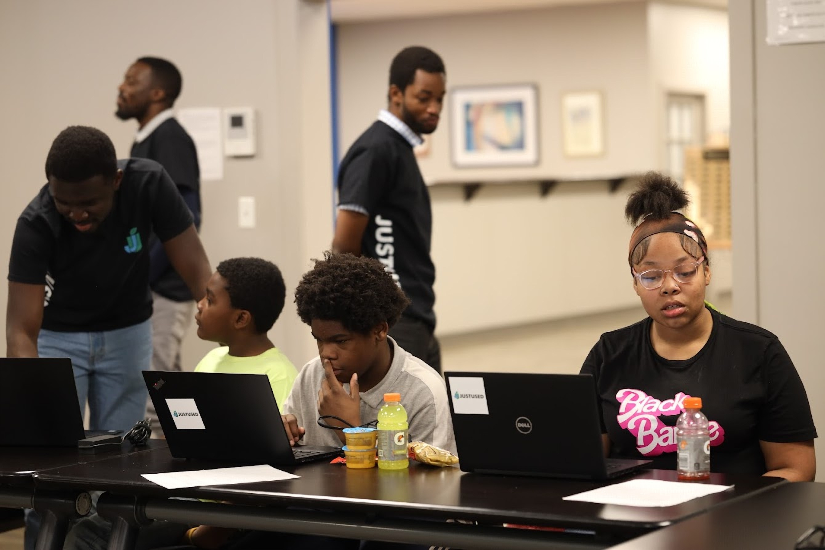 Students working on laptops at a JustUsedTech session, with a mentor helping.